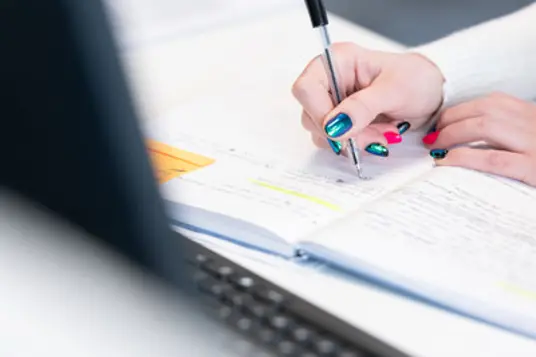 close up image of person writing notes in a notebook
